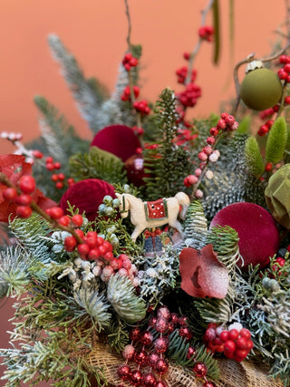 Christmas arrangement in natural wrap with red and green ornament