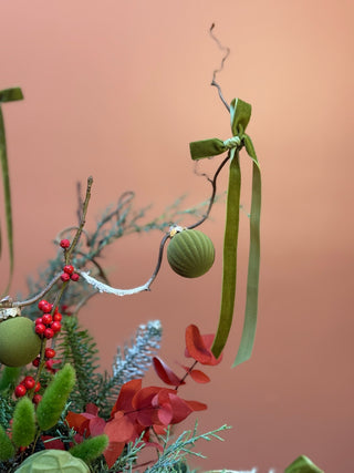 Christmas arrangement in natural wrap with red and green ornament